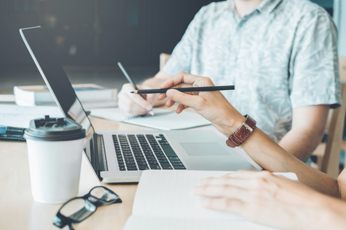 Zwei Menschen am Schreibtisch mit Laptop und Notizen