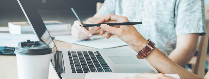 Zwei Menschen am Schreibtisch mit Laptop und Notizen